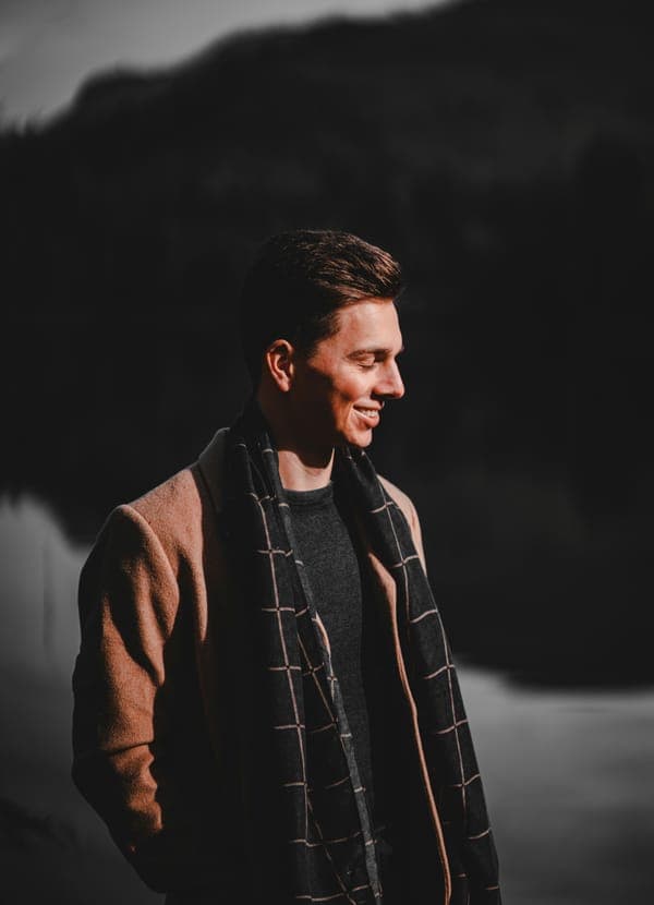 Marai Neesu in a camel coat and a checked scarf, smiling