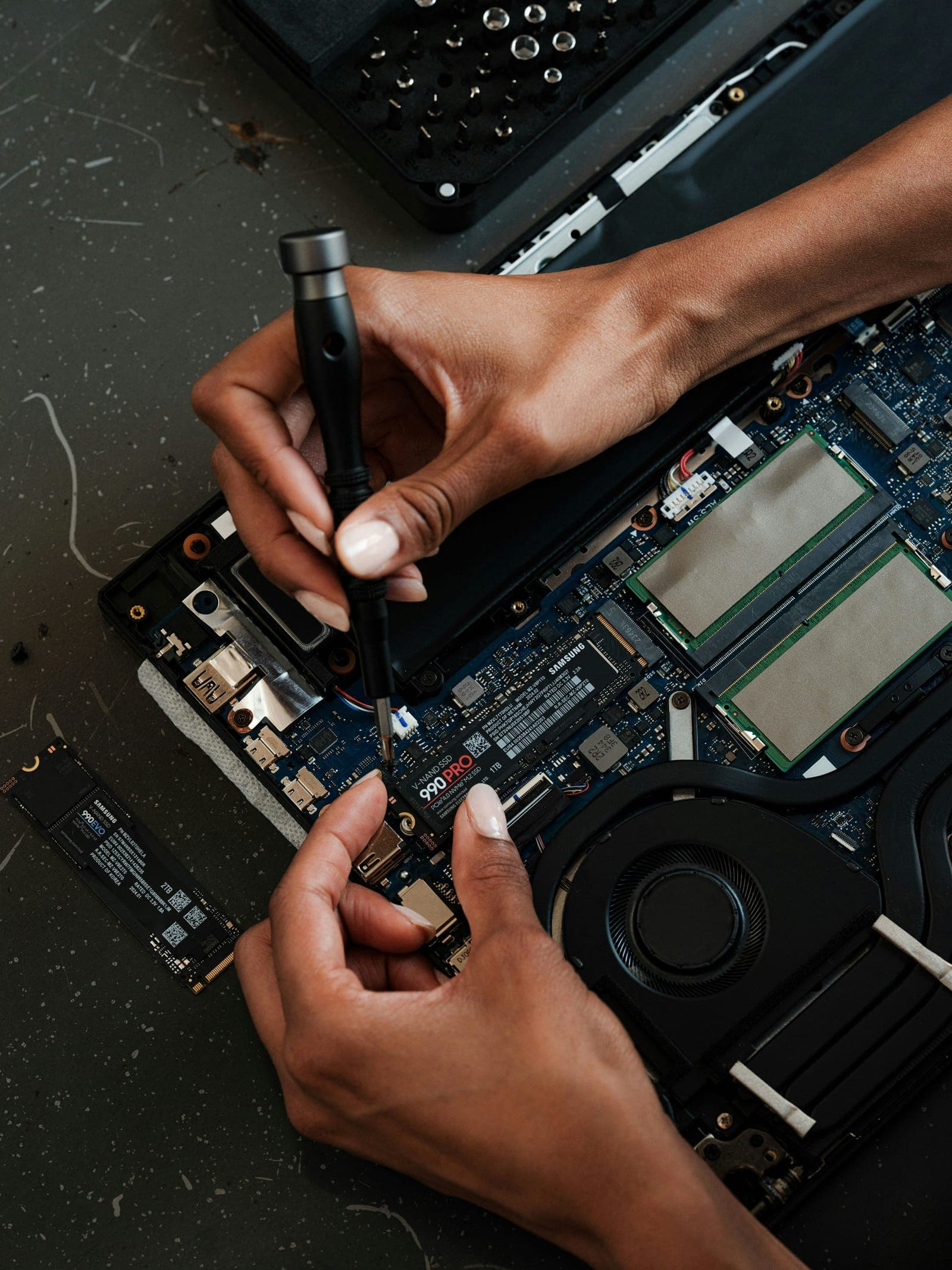 Hands repairing the inside of a laptop with a screwdriver
