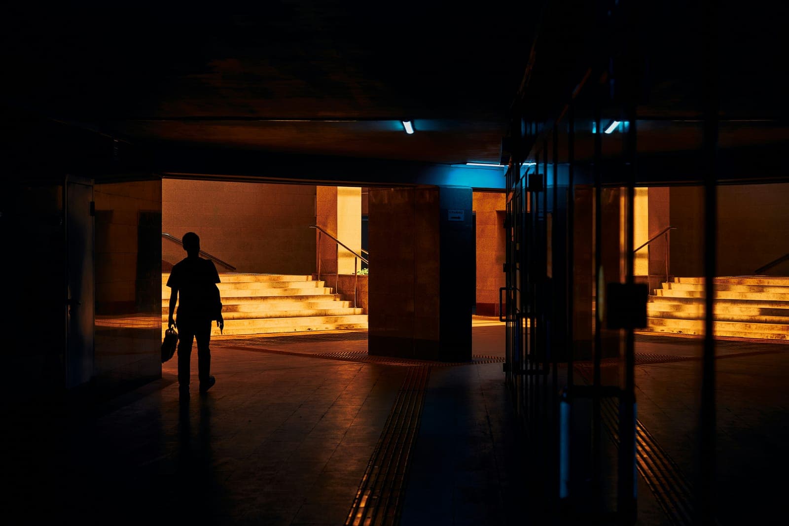 A person walking through a dark, lit doorway