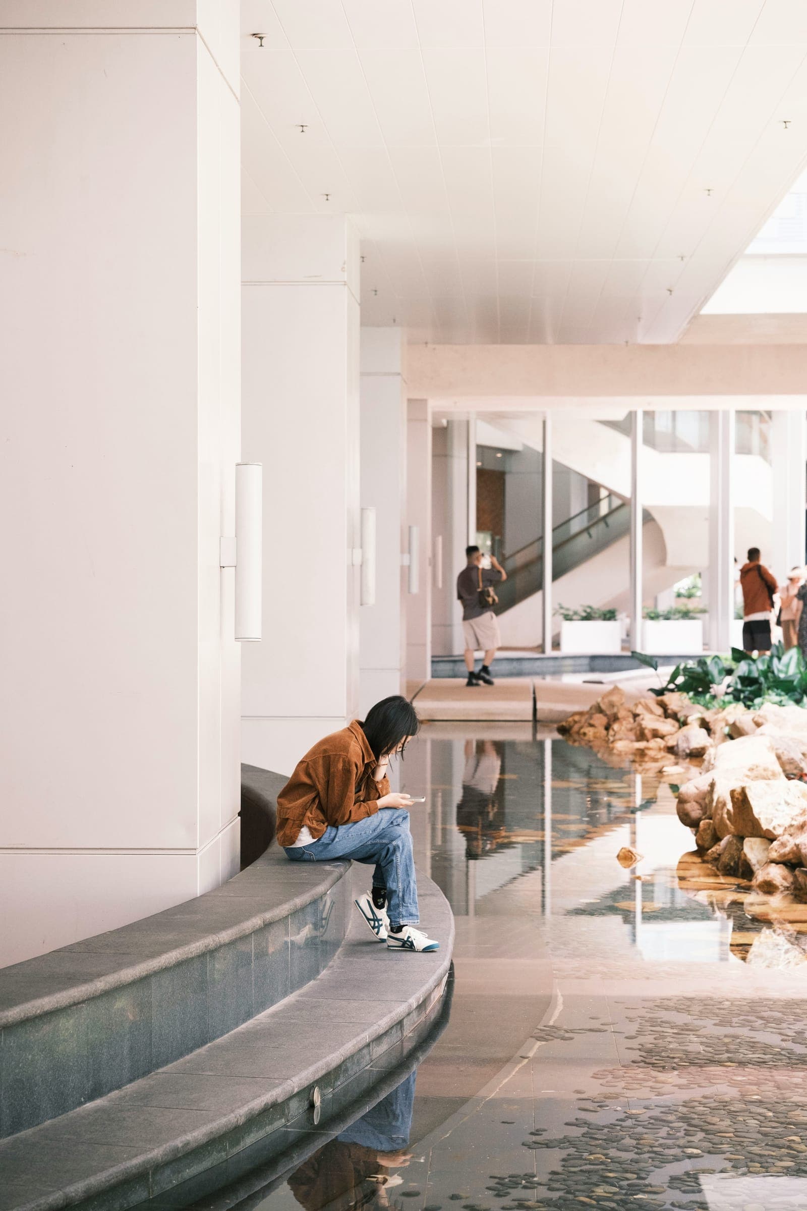 A person sitting with a phone in a bright modern lobby